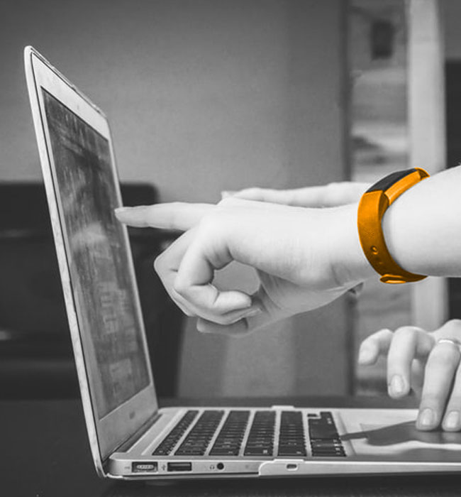 Photo noir et blanc illustrant l'accompagnement e-commerce que l'agence web Les Vikings à Lyon peut apporter à ses clients, on voit sur la photo les mains de deux personnes autour d'un même ordinateur et l'une des mains a une montre orange, couleur des Vikings, l'agence web.